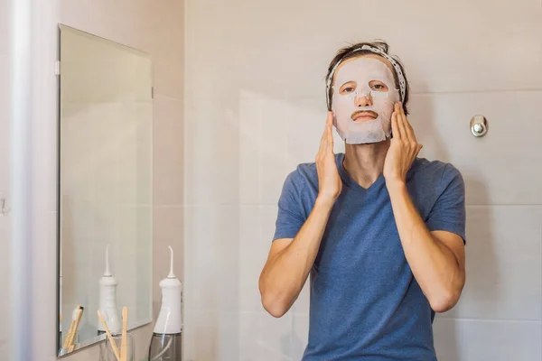 Young man doing facial mask sheet. Beauty and Skin Care Concept — Stock Photo, Image