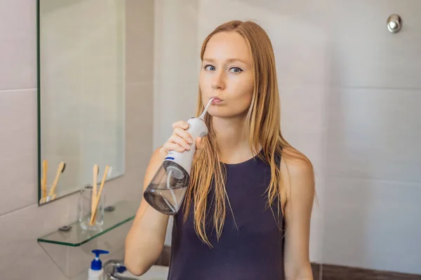 Woman using an oral irrigator in bathroom — Stock Photo, Image
