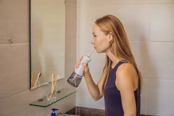Женщина, использующая оральный полив в ванной комнате — стоковое фото