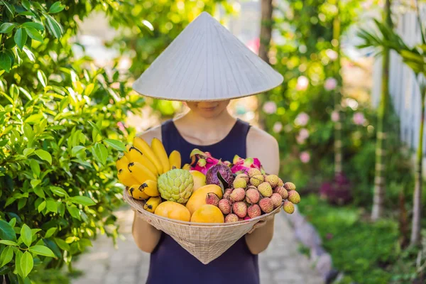 Variedad de frutas en un sombrero vietnamita. Mujer con sombrero vietnamita — Foto de Stock