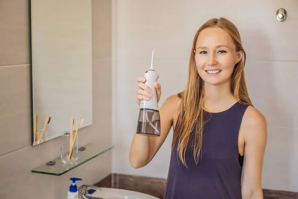 Woman using an oral irrigator in bathroom — Stock Photo, Image