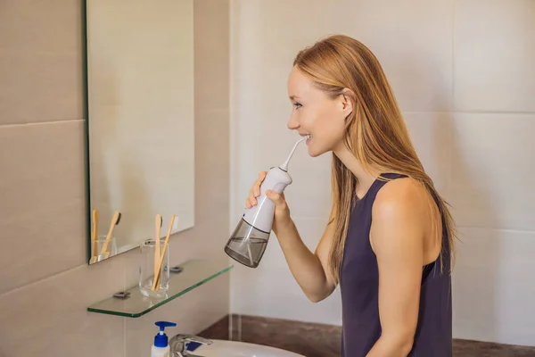 Woman using an oral irrigator in bathroom — Stock Photo, Image