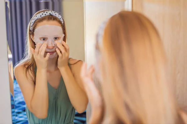 Young red-haired woman doing facial mask sheet. Beauty and Skin Care Concept — Stock Photo, Image