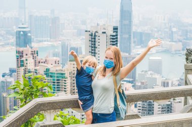 Anne ve oğul, Hong Kong 'un arka planına karşı Victoria' nın zirvesinde seyahat ediyorlar. Çocuk konseptiyle seyahat eden turistler 2019-ncov virüsünden korkuyorlar. Tıbbi maskeli turistler