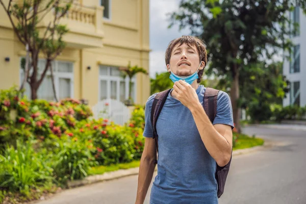 Quarantine is over concept. Man taking off mask against the background of small town houses. We are safe. Coronavirus ended. We won. No more quarantine. Breathe deep. Take off the mask. Coronavirus is — Stock Photo, Image