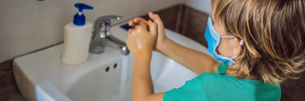 Boy washes his hands with soap. Boy in a medical mask due to coronavirus. Pandemic. Stay home. Wash your hands BANNER, LONG FORMAT — Stock Photo, Image