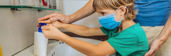 Dad teaches his son to wash his hands properly. Dad and son in medical masks because of coronovirus. Epidemic. Stay home. Wash your hands BANNER, LONG FORMAT