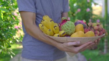 Vietnam şapkasındaki çeşitli meyveler. Vietnam şapkalı bir adamın elinde tropik meyvelerle dolu bir şapka var.