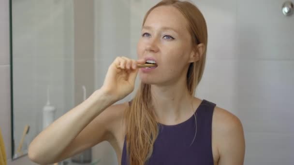 一个年轻的女人用竹木刷牙。零废物概念。可生物降解产品概念 — 图库视频影像