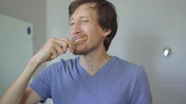 Un jeune homme se brosse les dents avec une brosse en bois de bambou. Concept zéro déchet. Concept de produits biodégradables — Video