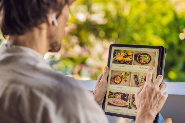 Adam tablet kullanarak öğle yemeği sipariş ediyor.