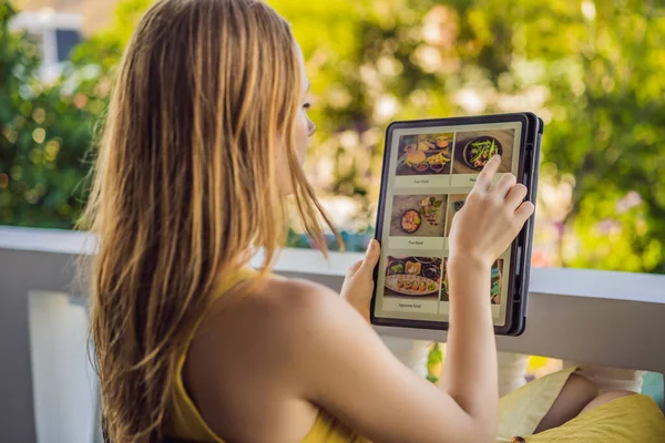 Young woman orders food for lunch online using Tablet