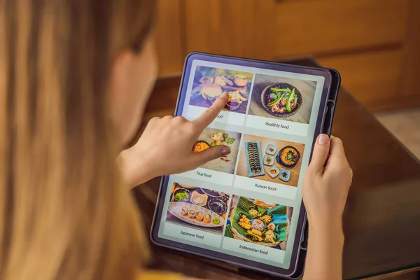 Młoda kobieta zamawia jedzenie na obiad online za pomocą tabletu — Zdjęcie stockowe