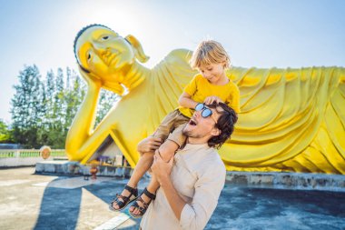 Coronavirus bitti. Karantina zayıfladı. Maskeni çıkar. Artık seyahat edebilirsin. Mutlu turistler baba ve oğul yalancı Buda heykelinin arka planında