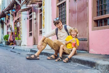 Coronavirus bitti. Karantina zayıfladı. Maskeni çıkar. Artık halka açık yerlere gidebilirsin. Baba ve oğul turistler Phuket Town 'daki Portekiz usulü Romani' de sokaktalar. Çin Mahallesi ya da