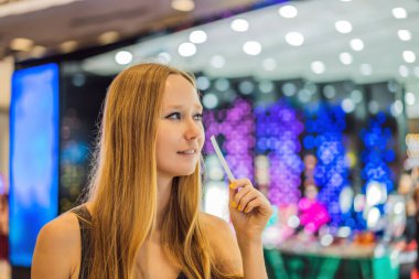 Coronavirus bitti. Karantina zayıfladı. Maskeni çıkar. Şimdi alışverişe gidebilirsin. Elinde kağıt şeritleri olan bir kadın alışveriş merkezindeki kokuyu dinler.