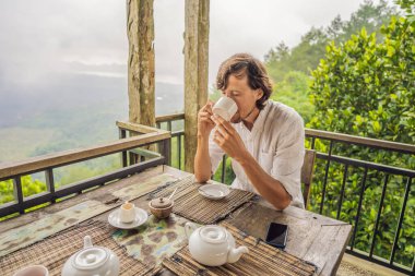 Coronavirus bitti. Karantina zayıfladı. Maskeni çıkar. Artık halka açık yerlere gidebilirsin. Dağdaki bir kafede çay içen adam.