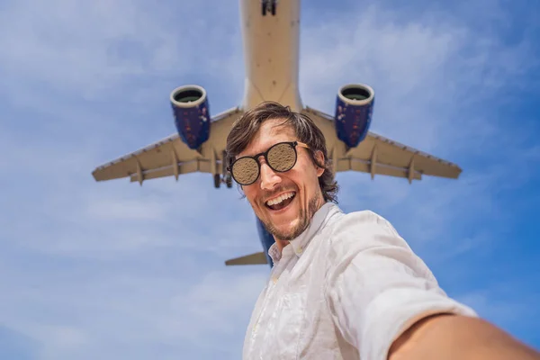 Das Coronavirus ist vorbei. Quarantäne geschwächt. Ziehen Sie die Maske ab. Jetzt kann man reisen. Ein Mann macht ein Selfie gegen den Himmel und ein fliegendes Flugzeug — Stockfoto