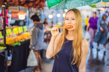 Coronavirus bitti. Karantina zayıfladı. Maskeni çıkar. Artık halka açık yerlere gidebilirsin. Yürüyen caddedeki Asya gıda pazarındaki genç kadın turist.