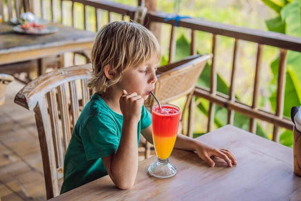 El coronavirus ha terminado. La cuarentena se debilitó. Quítate la máscara. Ahora puedes ir a lugares públicos. Chico bebe cóctel de dos tonos en una copa en el café — Foto de Stock