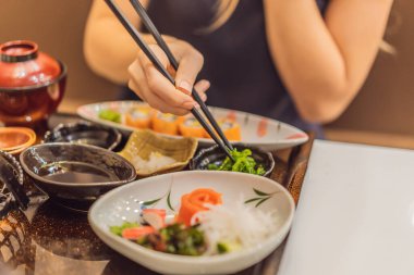 Coronavirus bitti. Karantina zayıfladı. Maskeni çıkar. Artık halka açık yerlere gidebilirsin. Japon lokantasında Japon yemeği yiyen bir kadın.