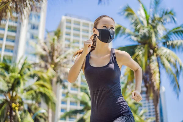 Woman runner wearing medical mask. Running in the city against the backdrop of the city. Coronavirus pandemic Covid-19. Sport, Active life in quarantine surgical sterilizing face mask protection — Stock Photo, Image