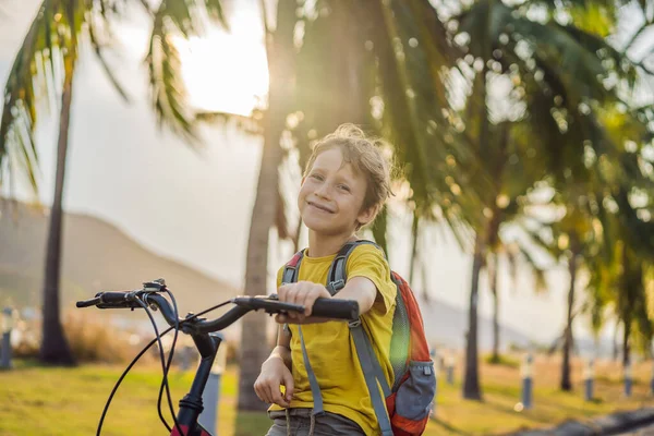 Aktivní školák na kole s batohem za slunečného dne. Šťastné dítě na kole na cestě do školy. Bezpečný způsob pro děti venku do školy — Stock fotografie
