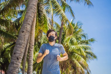 Tıbbi maske takan bir koşucu. Parkta koşmak. Coronavirus salgını Covid-19. Spor, karantinada aktif yaşam yüz maskesi korumalı cerrahi sterilizasyon. Atletizm pistinde açık hava koşusu