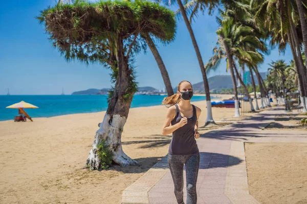 Corredor mulher usando máscara médica. A correr no parque. pandemia de coronavírus Covid-19. Esporte, vida ativa em quarentena cirúrgica esterilizando proteção máscara facial. Corrida ao ar livre na pista de atletismo em — Fotografia de Stock