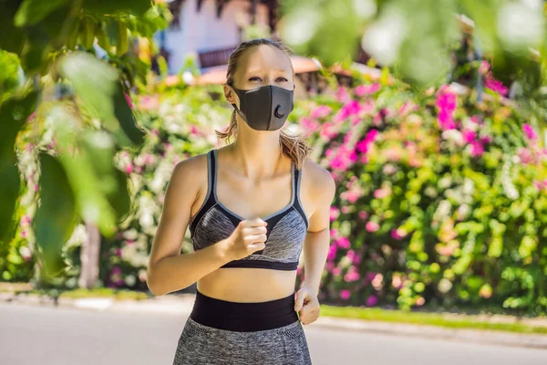 Läuferin mit medizinischer Maske. Laufen im Park. Coronavirus-Pandemie Covid-19. Sport, Aktives Leben in der chirurgischen Quarantäne, sterilisierender Mundschutz. Outdoor-Lauf auf Leichtathletik-Bahn in — Stockfoto