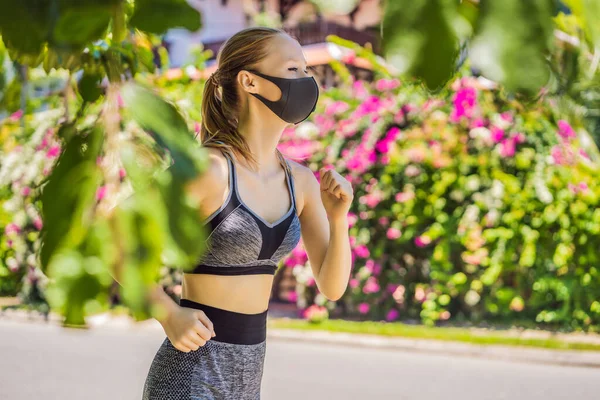 Läuferin mit medizinischer Maske. Laufen im Park. Coronavirus-Pandemie Covid-19. Sport, Aktives Leben in der chirurgischen Quarantäne, sterilisierender Mundschutz. Outdoor-Lauf auf Leichtathletik-Bahn in — Stockfoto