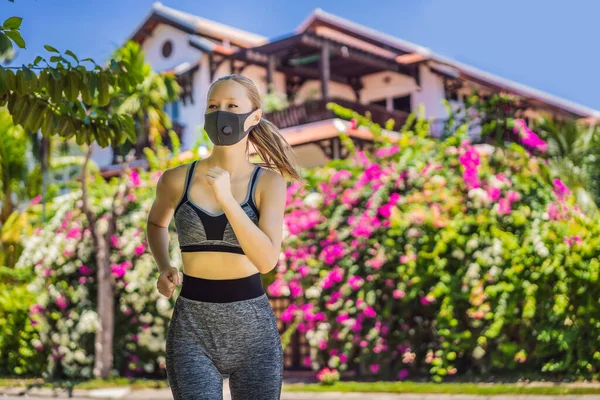 Woman runner wearing medical mask. Running in the park. Coronavirus pandemic Covid-19. Sport, Active life in quarantine surgical sterilizing face mask protection. Outdoor run on athletics track in