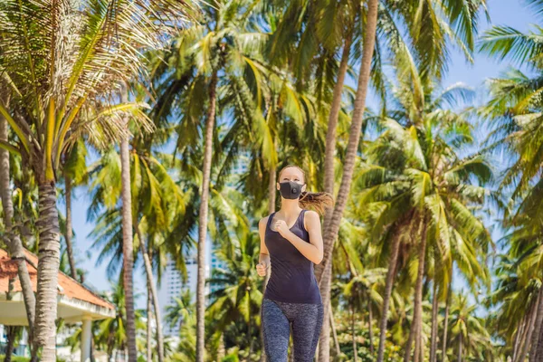 Läuferin mit medizinischer Maske. Laufen im Park. Coronavirus-Pandemie Covid-19. Sport, Aktives Leben in der chirurgischen Quarantäne, sterilisierender Mundschutz. Outdoor-Lauf auf Leichtathletik-Bahn in — Stockfoto