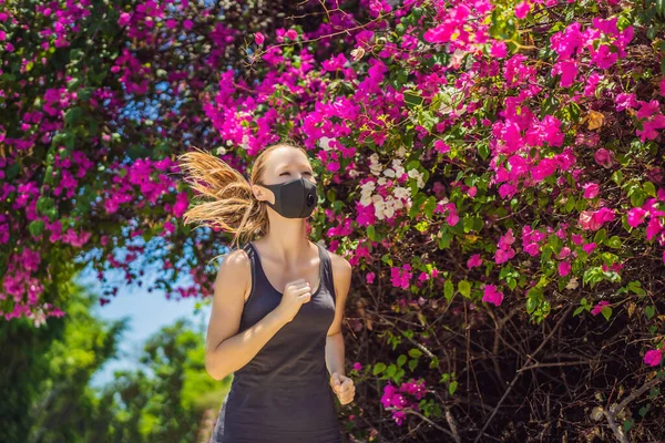 Woman runner wearing medical mask. Running in the park. Coronavirus pandemic Covid-19. Sport, Active life in quarantine surgical sterilizing face mask protection. Outdoor run on athletics track in