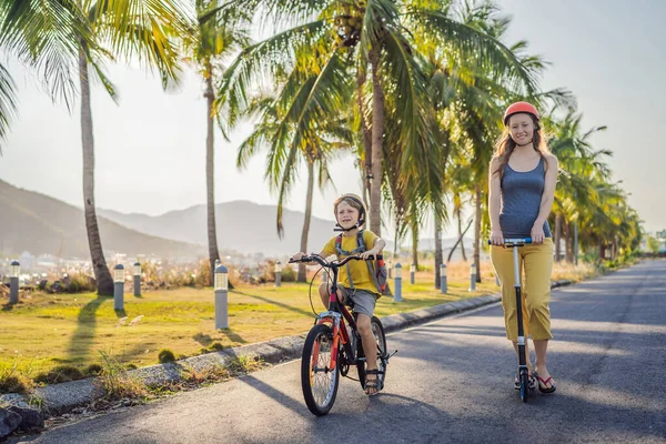 Ενεργό παιδί του σχολείου αγόρι και η μαμά του σε κράνος ασφαλείας οδήγηση ενός ποδηλάτου με σακίδιο στην ηλιόλουστη μέρα. Ευτυχισμένο ποδήλατο στο δρόμο για το σχολείο. Ασφαλής τρόπος για τα παιδιά σε εξωτερικούς χώρους στο σχολείο — Φωτογραφία Αρχείου