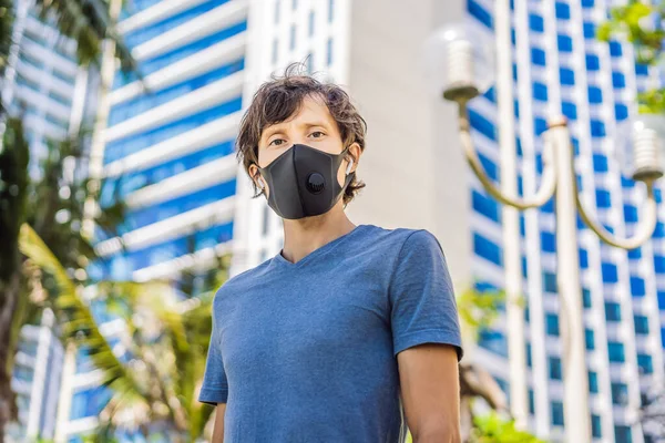 Fashionable black medical mask with filter in the city. Coronavirus 2019-ncov epidemic concept. Man in a black medical mask. Portrait of a man with expressive eyes during a virus or disease epidemic