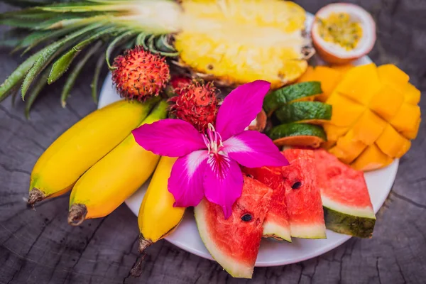Frutas tropicais coloridas em prato grande. No fundo de madeira rústico. Vista superior — Fotografia de Stock
