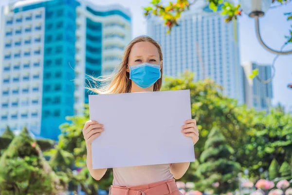 Kobieta w masce medycznej zapobiega chorobom koronawirusowym posiada plakat z darmowymi napisami. Przestrzeń COPY — Zdjęcie stockowe