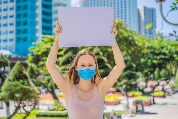 Nő orvosi maszkban megakadályozza a koronavírus betegség rendelkezik egy poszter ingyenes feliratok. COPY szóköz — Stock Fotó