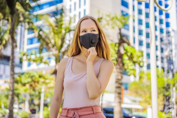 Máscara médica preta na moda com filtro na cidade. Conceito de epidemia de Coronavirus 2019-ncov. Mulher com uma máscara médica preta. Retrato de uma mulher com olhos expressivos durante um vírus ou doença — Fotografia de Stock