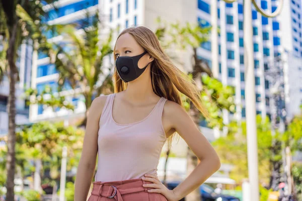 Fashionable black medical mask with filter in the city. Coronavirus 2019-ncov epidemic concept. Woman in a black medical mask. Portrait of a woman with expressive eyes during a virus or disease