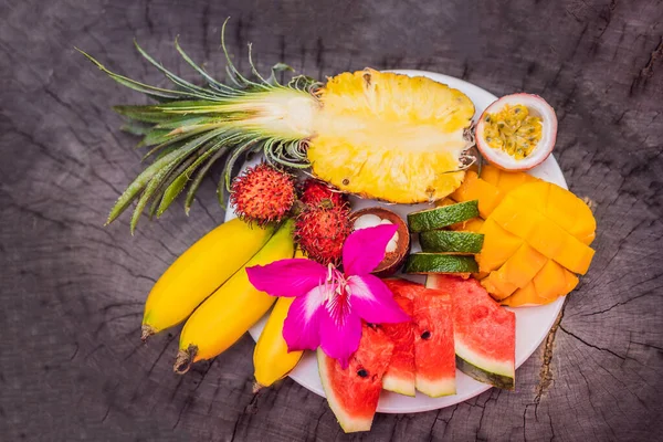 Kleurrijke tropische vruchten op grote schaal. Op rustieke houten ondergrond. Bovenaanzicht — Stockfoto