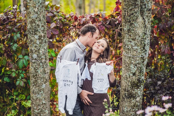 Une jeune femme enceinte et son mari. Une famille heureuse accrochant des vêtements de bébé pour sécher sur une corde. femme enceinte se détendre dans le parc . — Photo