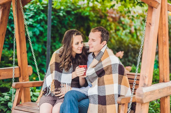 Een zwangere jonge vrouw en haar man. Een gelukkig gezin zittend op een schommel, buikje vasthoudend. zwangere vrouw ontspannen in het park. — Stockfoto