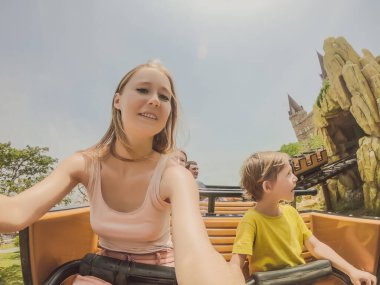 Anne ve oğlu lunapark treninde eğleniyor.