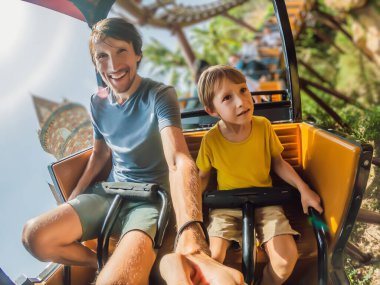 Baba oğul lunapark treninde eğleniyorlar.