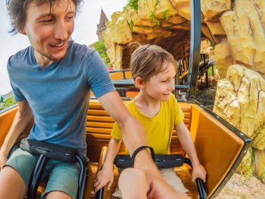 Baba oğul lunapark treninde eğleniyorlar.