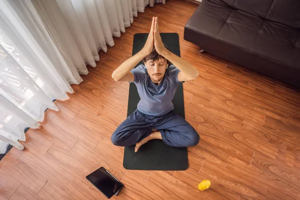 Fitness man exercising on the floor at home and watching fitness videos in a tablet. People do sports online because of the coronovirus — Stock Photo, Image