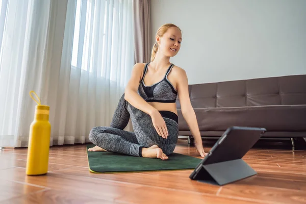 Spor salonundaki kadın evde egzersiz yapıyor ve tabletle spor salonu videoları izliyor. İnsanlar koronovirüs yüzünden spor yapıyor. — Stok fotoğraf