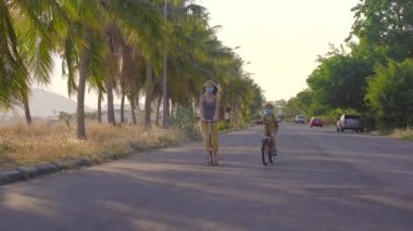 Aktif okul çocuğu ve annesi güneşli bir günde bisiklet ve scooter sürüyorlar. Okula giderken mutlu çocuk bisikleti. Çocuklar için okul için güvenli bir yol. Okullar kapatıldıktan sonra açılır.